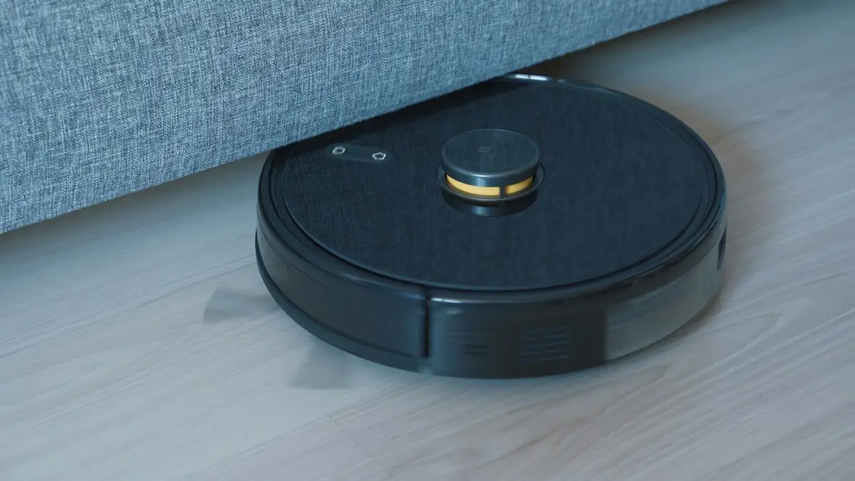 Black robot vacuum on a wooden floor