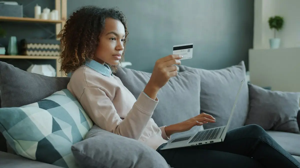 Woman shopping online with laptop and card on a sofa