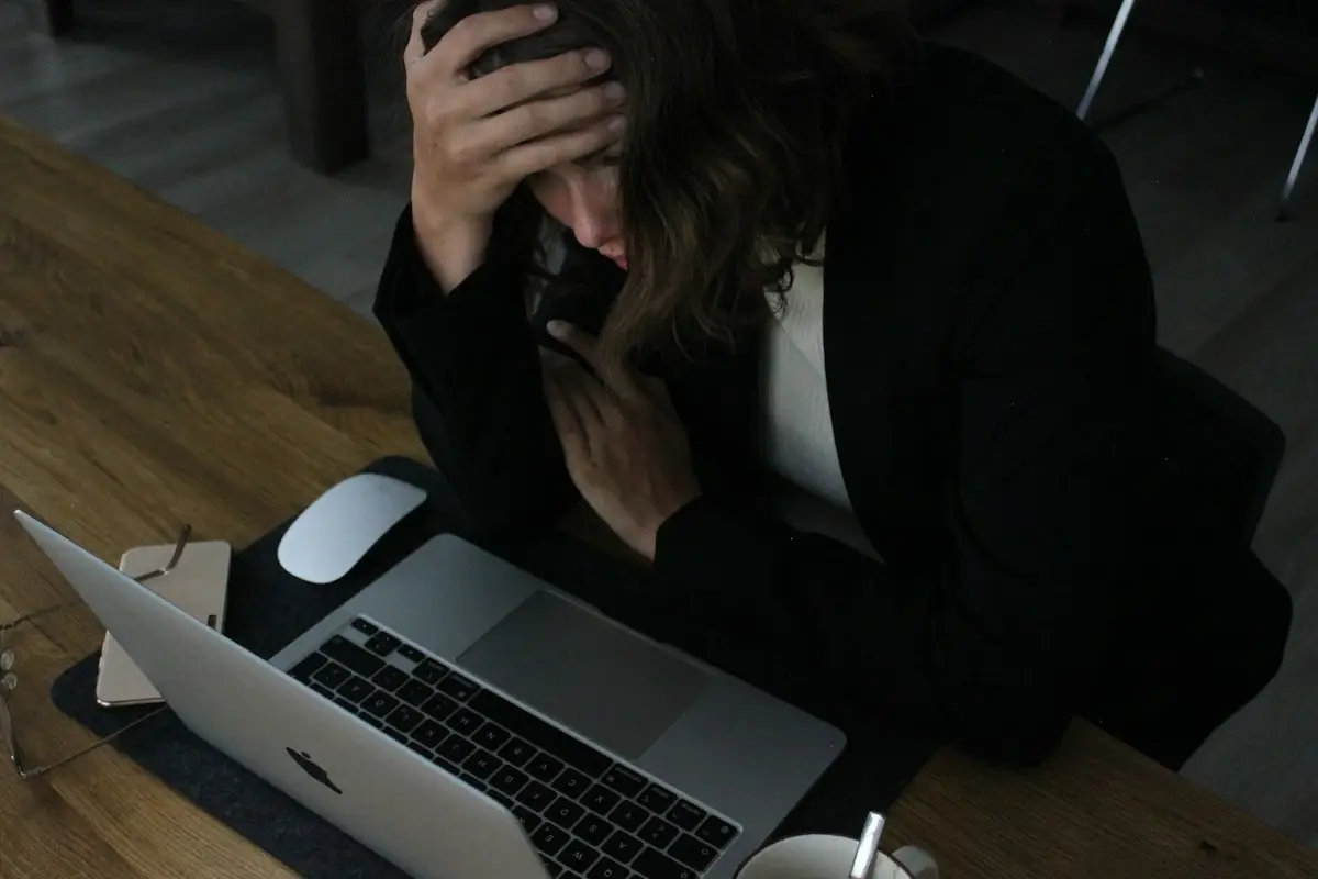 Frustrated woman with head in hands at a laptop